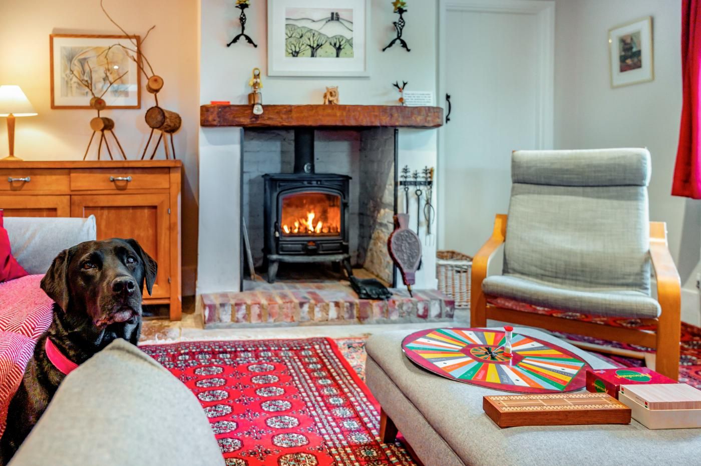 A cozy living room with a fireplace, a dog, a comfortable armchair, and a colorful game board.
