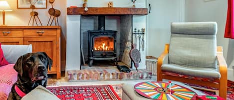 A cozy living room with a fireplace, a dog, a comfortable armchair, and a colorful game board.