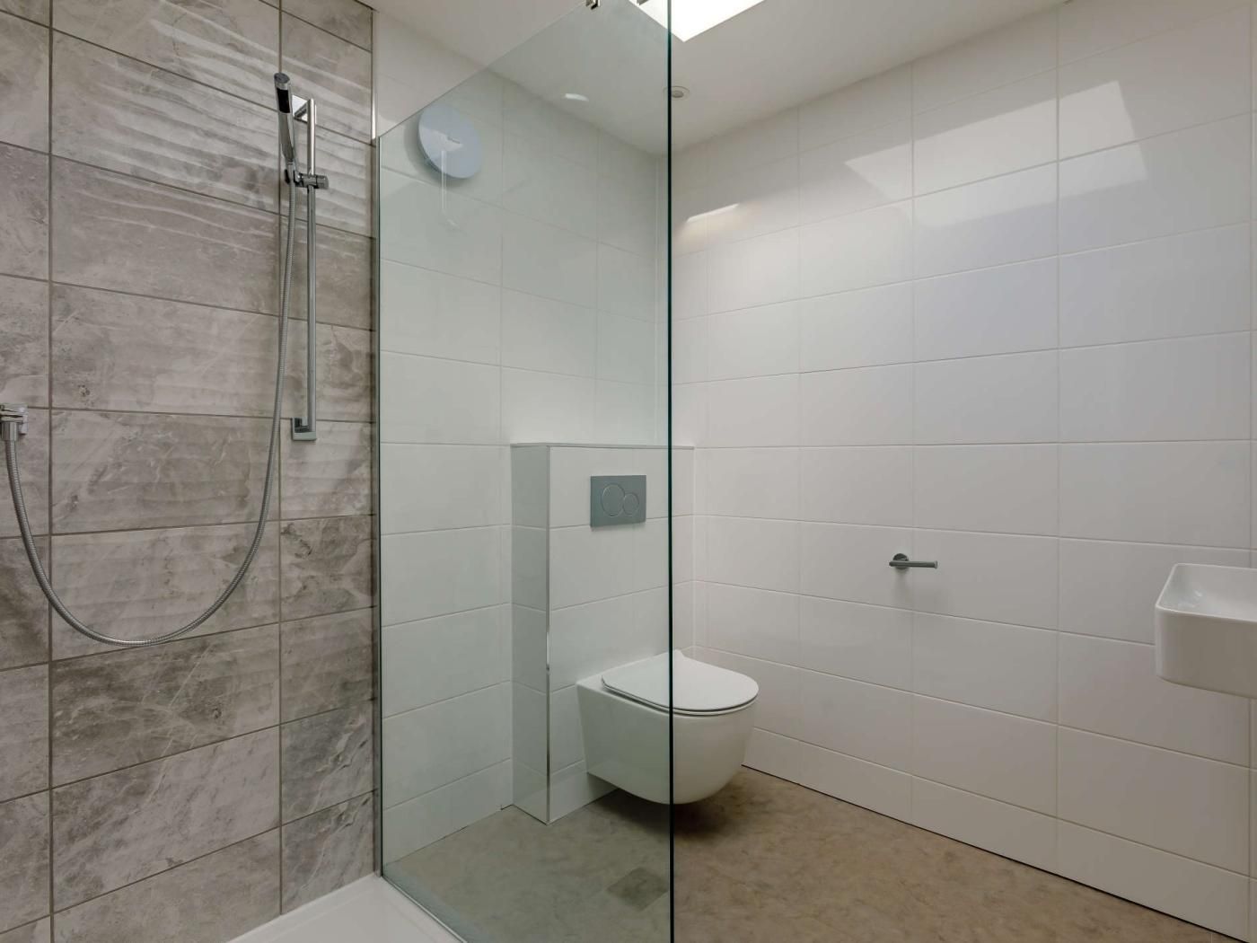 A modern bathroom with a glass shower enclosure, a toilet, and a sink.