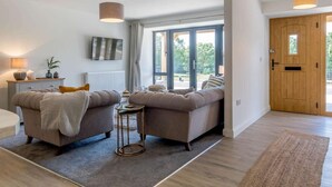 Ein modernes Wohnzimmer mit zwei Sofas, einem Couchtisch, einem Fernseher und einem großen Fenster.