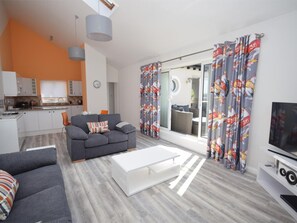 A modern living room with a grey sofa, a white coffee table, and a TV stand. - 1 Bed in Swanage (oc-dc124) (Swanage)