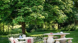 Un jardín con un banco de metal, una mesa y una mesa de piedra.