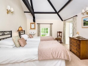 A bedroom with two beds, a wooden dresser, a nightstand, a lamp, a mirror, and a window with curtains. - 6 Bed in Workington (oc-sz151) (Lamplugh)