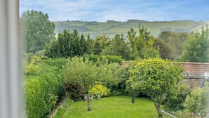 Ein Garten mit Rasenfläche, Bäumen und einer Steinmauer.
