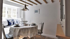 Un comedor con una mesa redonda, sillas y una lámpara colgante.
