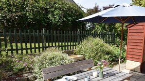 Una panchina di legno con un tavolo, un'area picnic e un giardino con una recinzione in legno.