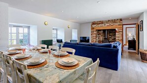 Un comedor con una mesa dispuesta para cuatro personas, un sofá azul y una chimenea de ladrillo.