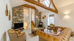 Ein geräumiger Wohnbereich mit Kamin aus Stein, Ledersofas und einem Fernseher.