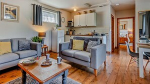 A cozy living room with a sofa, coffee table, and a dining area with a chair and table. - 1 Bed in Dorchester (oc-75157) (Winfrith Newburgh)