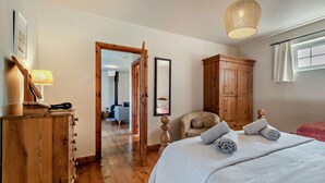 A bedroom with a wooden dresser, a bed with rolled towels, a chair, and a wardrobe. - 1 Bed in Dorchester (oc-75157) (Winfrith Newburgh)