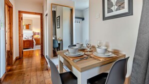 A dining area with a wooden table set for two, a mirror, and a framed artwork on the wall. - 1 Bed in Dorchester (oc-75157) (Winfrith Newburgh)