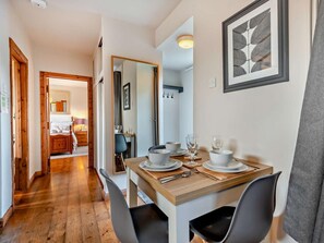 A dining area with a wooden table set for two, a mirror, and a framed artwork on the wall. - 1 Bed in Dorchester (oc-75157) (Winfrith Newburgh)