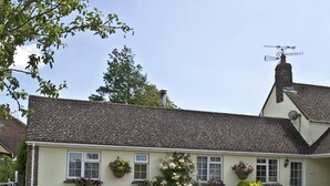 Um edifício de dois andares com telhado inclinado, várias janelas e floreiras.
