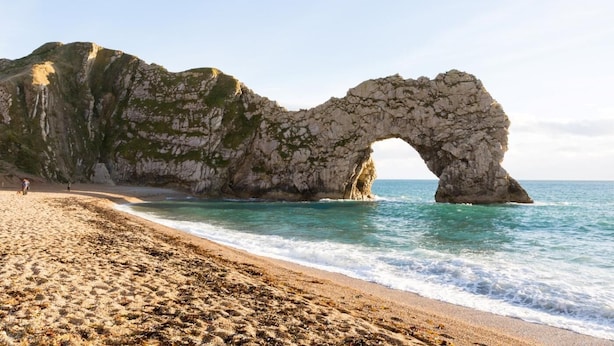 Uma praia com um arco natural de rocha.