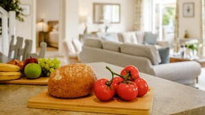 Una encimera de cocina con pan, tomates y plátanos.