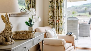 Una habitación con sofá, lámpara, cesta de mimbre, planta en maceta y silla de mimbre.