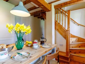 A wooden dining table with a vase of yellow flowers, a coffee maker, and various dishes. - 2 Bed in Chulmleigh (oc-75412) (Ashreigney)