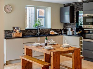 Una cucina moderna con tavolo in legno apparecchiato per mangiare, una finestra con vista e elettrodomestici integrati.