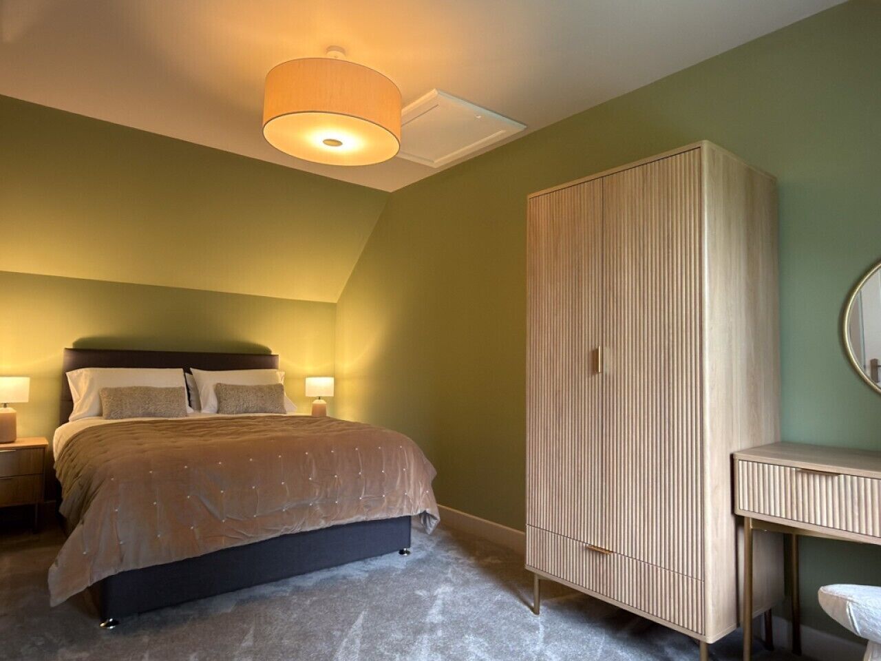 A bedroom with a bed, bedside lamps, a wardrobe, and a mirror.