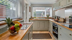 A modern kitchen with a wooden countertop, a fruit bowl, a window with blinds, and a built-in oven. - 3 Bed in Norwich (oc-75160) (Mundesley)