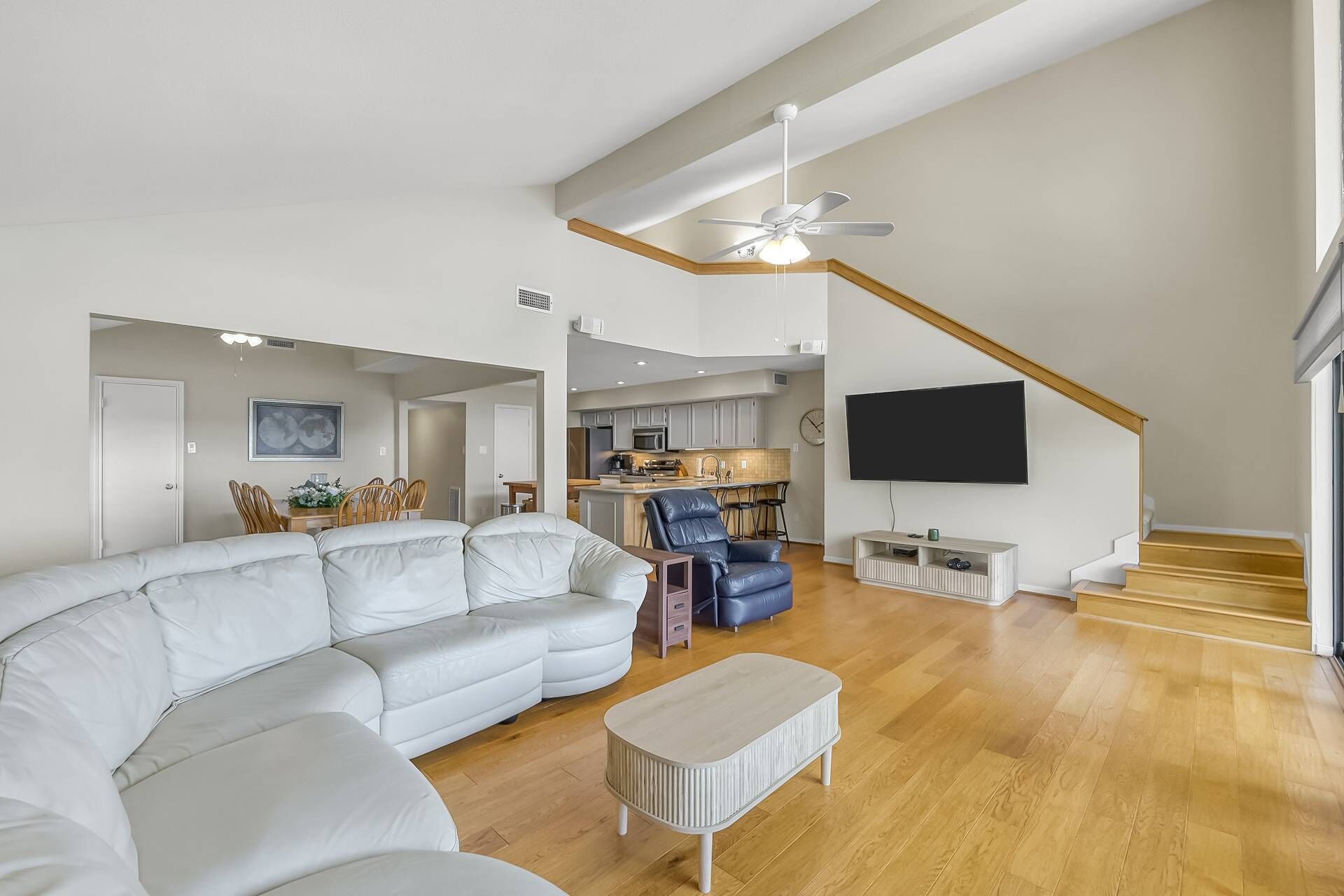 Una sala moderna con un sofá modular, una mesa de centro, un televisor y una escalera.