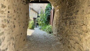 A narrow stone passageway with a gravel path leading to a building.