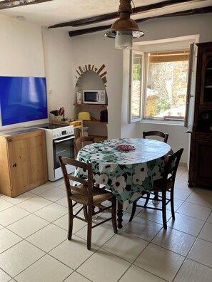 A kitchen with a dining table, chairs, a microwave, and a window.