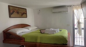 A single bed with a green bedspread, white pillows, and a framed artwork above it. - Sweet Home A&C (Conversano)