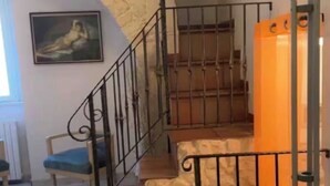 Una escalera con barandillas metálicas, un muro de piedra y un cuadro en la pared.