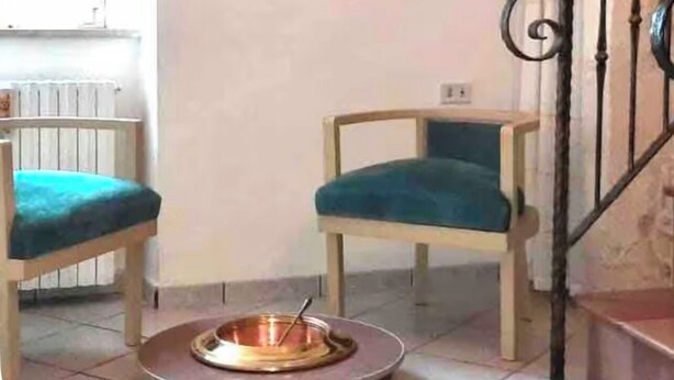 Una habitación con dos sillas, un cuadro en la pared, un radiador y una escalera.