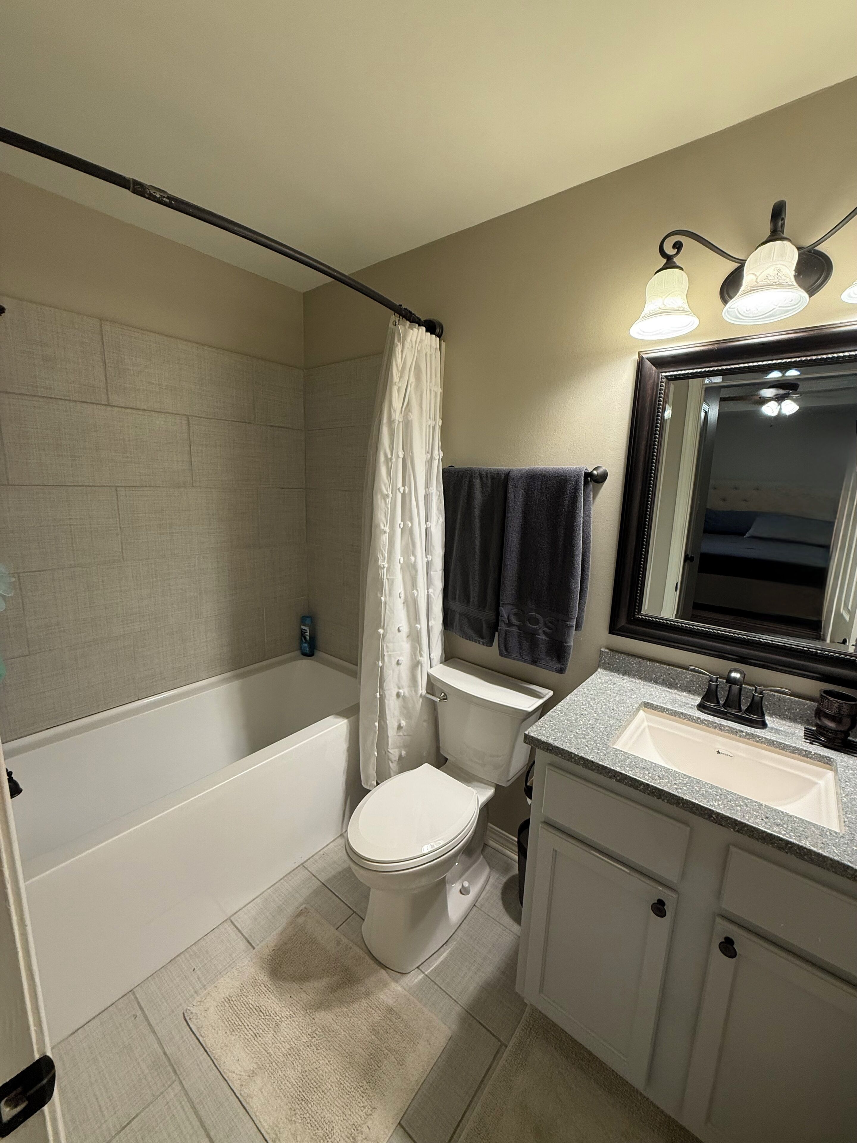 A bathroom with a bathtub, toilet, sink, and a mirror.