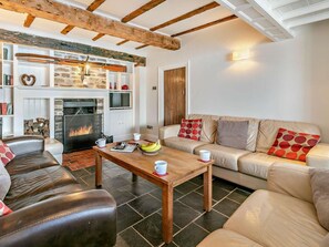 A cozy living room with a fireplace, leather sofas, a wooden coffee table, and a stone fireplace surround. - 6 Bed in Fowey (oc-75581) (Fowey)