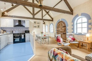 Eine geräumige Küche mit modernen Geräten, ein Essbereich mit Tisch und Stühlen sowie eine gemütliche Sitzecke mit Sofa und Sesseln.