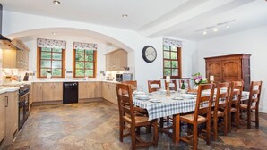 A kitchen with a dining area, stone flooring, wooden cabinets, and a clock on the wall. - 5 Bed in Worcester (oc-75602) (Halmond's Frome)