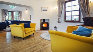 A cozy living room with a fireplace, yellow sofas, and a large window with curtains. - 5 Bed in Worcester (oc-75602) (Halmond's Frome)