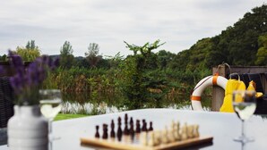 A chessboard on a table with a view of a lake and greenery in the background. - 5 Bed in Worcester (oc-75602) (Halmond's Frome)