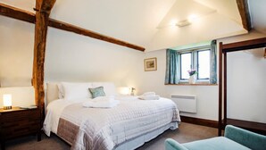A bedroom with a large bed, a nightstand, a chair, a window with curtains, and a picture on the wall. - 1 Bed in Worcester (oc-75600) (Halmond's Frome)