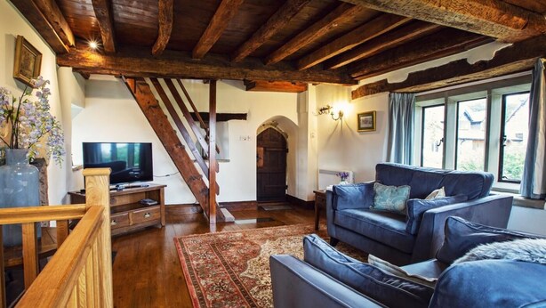 A cozy living room with a wooden staircase, a sofa, a television, and a large window. - 1 Bed in Worcester (oc-75600) (Halmond's Frome)
