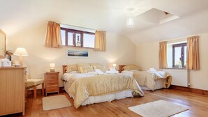 Camera da letto con due letti, pavimento in legno, termosifone e finestra con tende.