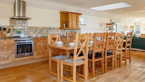 Una cucina moderna con mobili in legno, un forno in acciaio inossidabile e un'area pranzo con sedie di legno.