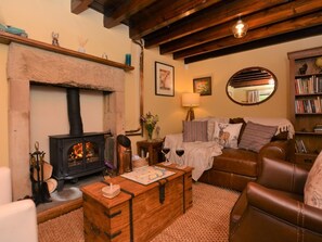 Ein gemütliches Wohnzimmer mit Kamin, Ledersofa, Couchtisch aus Holz und Bücherregal.