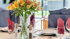 A dining table set with plates, glasses, and a vase of flowers. - 3 Bed in Penzance (oc-75635) (Gulval)