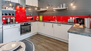 A modern kitchen with white cabinets, a red backsplash, and stainless steel appliances. - 3 Bed in Penzance (oc-75635) (Gulval)