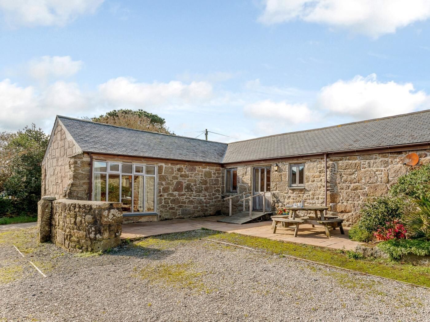 A stone building with a gravel driveway and a patio area with outdoor seating.