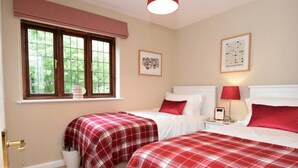 A bedroom with two beds, a window with blinds, a bedside table with a lamp, and a framed picture on the wall. - 2 Bed in Shipston-on-stour (oc-75870) (Whichford)