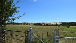 A rural landscape with a metal gate and fence, a clear sky, and distant fields. - 2 Bed in Shipston-on-stour (oc-75870) (Whichford)