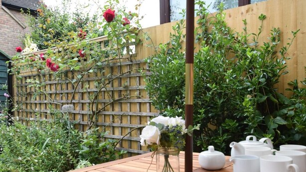 A wooden table with a vase of flowers and white teapots. - 2 Bed in Shipston-on-stour (oc-75870) (Whichford)