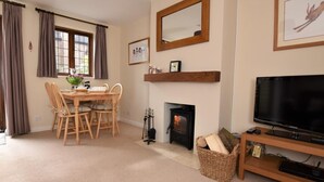 A cozy living room with a fireplace, a dining area with wooden furniture, and a television on a wooden stand. - 2 Bed in Shipston-on-stour (oc-75870) (Whichford)