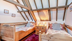 Ein Schlafzimmer mit zwei Holzbetten, einem Schminktisch und einer schrägen Decke mit freiliegenden Balken.