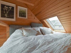 A bedroom with a sloped ceiling, wooden walls, a bed with white bedding, two pillows, and a window. - 1 Bed in Pitlochry (oc-75678) (Pitlochry)